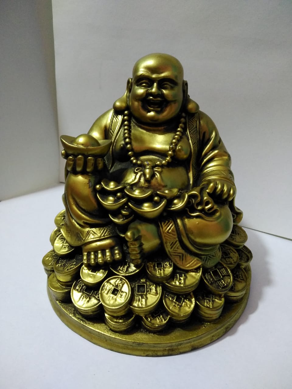 laughing buddha sitting on coins